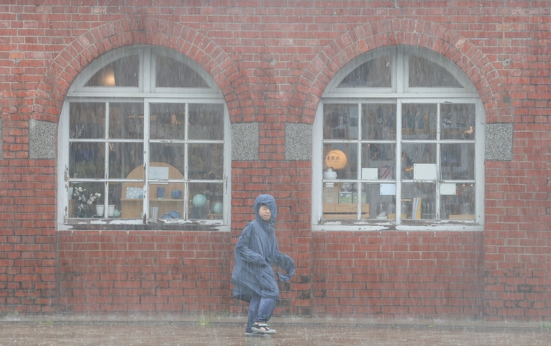 圖為台北市中正區大雨滂沱，小朋友穿雨衣冒雨前行。（中央社記者謝佳璋攝）