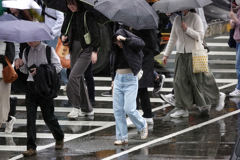 圖為台北市南港軟體園區民眾用外套遮擋雨勢。（圖源：中央社記者鄭傑文攝）