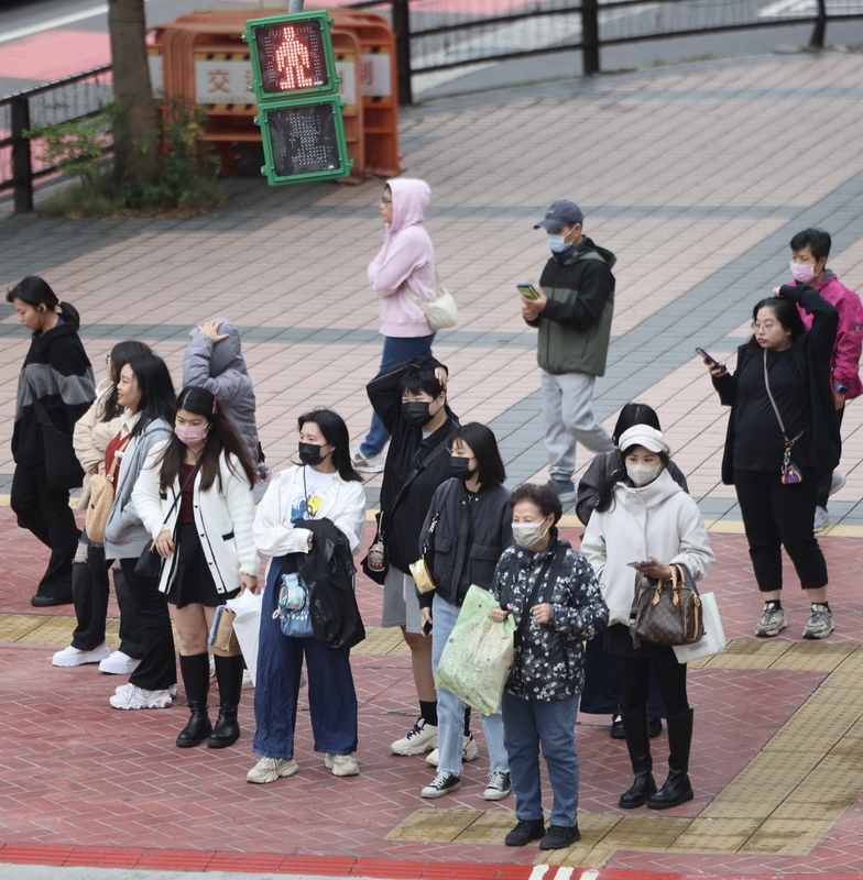 圖為新北市板橋區民眾穿著外套禦寒。( 中央社記者趙世勳攝 )