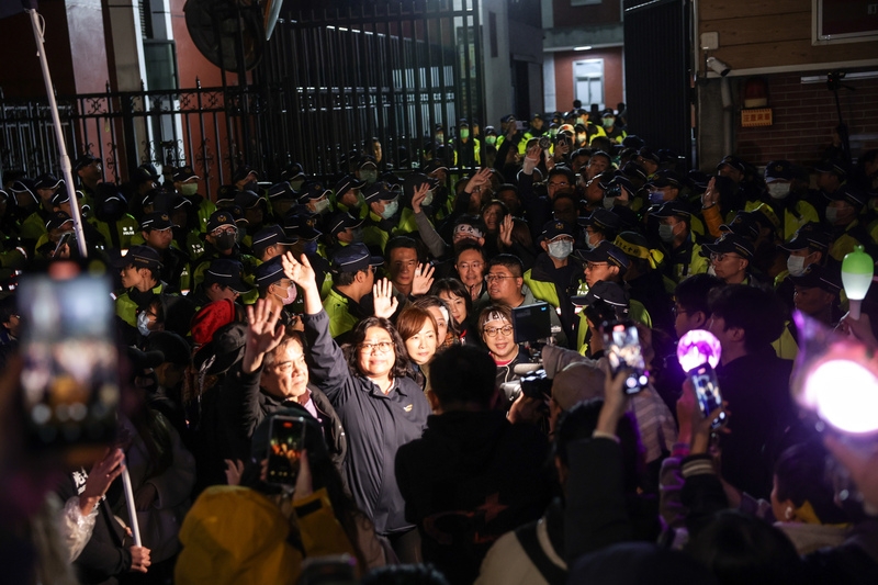 立法院20日爆發嚴重肢體衝突，但民眾黨立委黃國昌表示，這都是民進黨的「兩面手法」，暴力癱瘓國會的背後是與國民黨的一場失敗交易。圖為民進黨立委在立法程序結束後，於警力包圍下到場外向堅守到底的青鳥們揮手致意。（中央社提供）