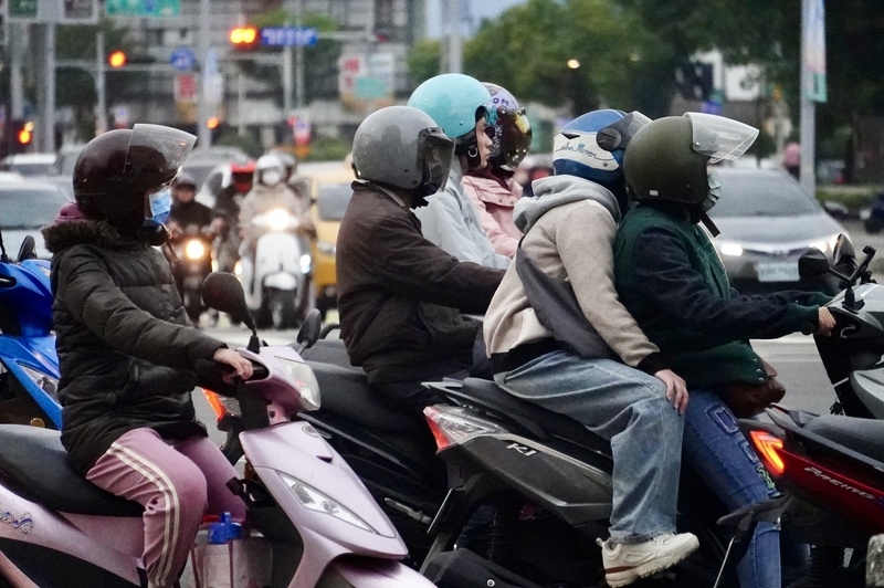 圖為高雄街頭機車騎士穿起保暖外套騎車。(中央社記者董俊志攝)