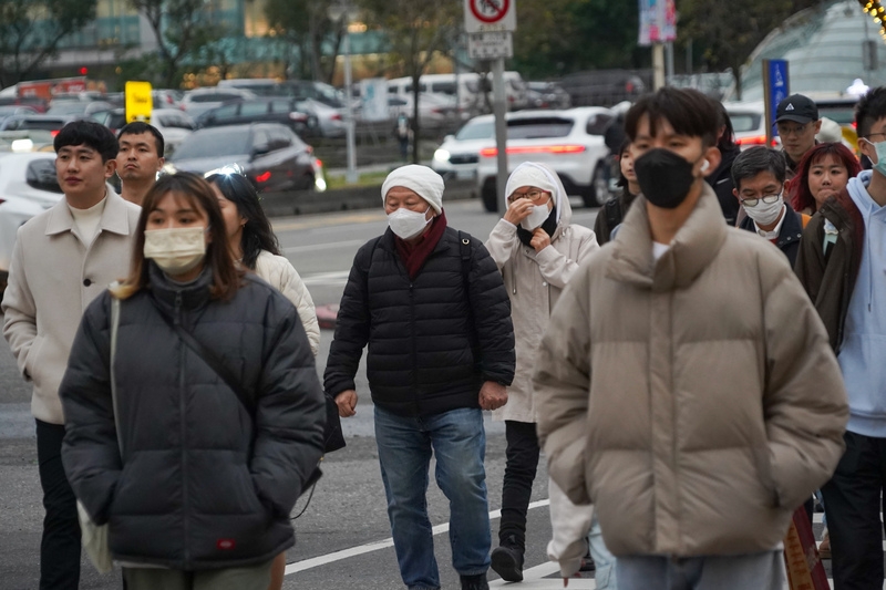 圖為台北市信義區街頭滿是穿著厚外套、戴口罩防寒的民眾。( 中央社記者裴禛攝)